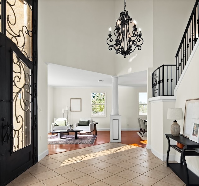 entryway featuring ornate columns, a towering ceiling, and light tile patterned flooring