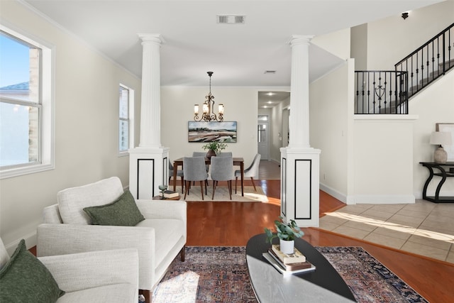 living room featuring ornamental molding, hardwood / wood-style flooring, a chandelier, and ornate columns