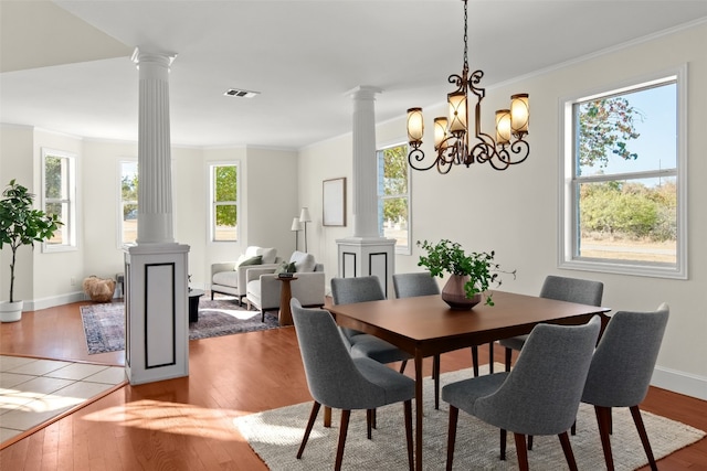 dining room featuring a healthy amount of sunlight, ornate columns, and hardwood / wood-style flooring