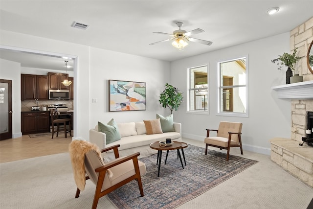 carpeted living room featuring a fireplace and ceiling fan