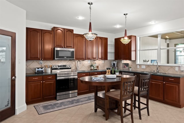 kitchen featuring decorative backsplash, light tile patterned flooring, sink, pendant lighting, and stainless steel appliances