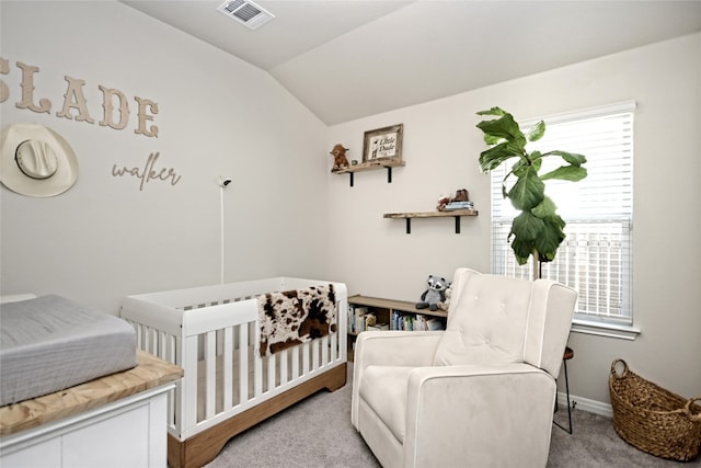 carpeted bedroom featuring vaulted ceiling and a crib