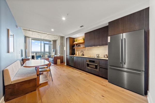 48 E Ave Unit 2511, Austin, TX 78701 - kitchen featuring appliances with stainless steel finishes, dark brown cabinets, light countertops, tasteful backsplash, and light wood-style floors