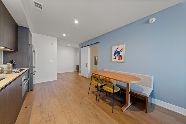 kitchen with appliances with stainless steel finishes, light hardwood / wood-style floors, and a barn door