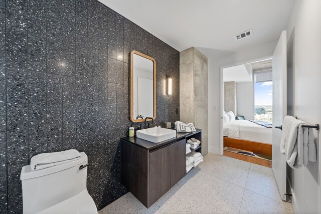 bathroom featuring vanity, tile walls, and toilet