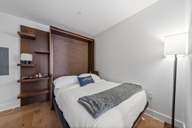 bedroom featuring vaulted ceiling, electric panel, and hardwood / wood-style floors