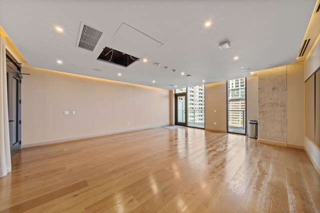 spare room with a wall of windows and light hardwood / wood-style floors