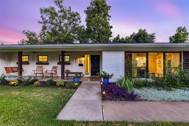 ranch-style house featuring covered porch and a lawn