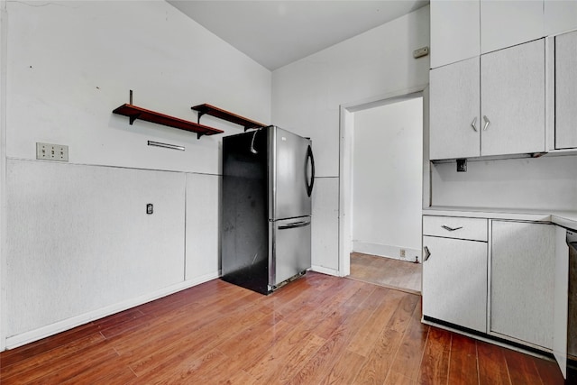 kitchen with light wood-type flooring, white cabinets, and stainless steel refrigerator