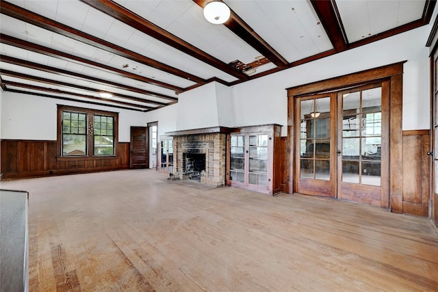 unfurnished living room with light hardwood / wood-style floors, beam ceiling, a brick fireplace, and plenty of natural light