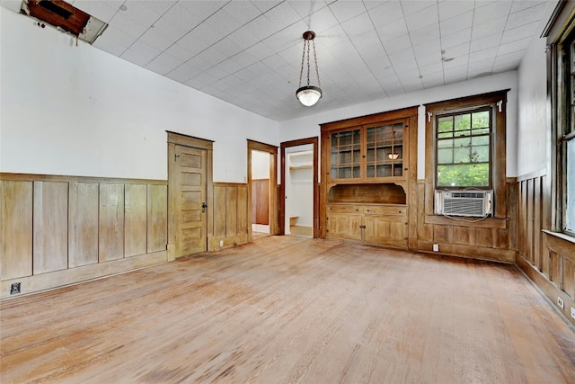 interior space with cooling unit, wood walls, and light hardwood / wood-style flooring