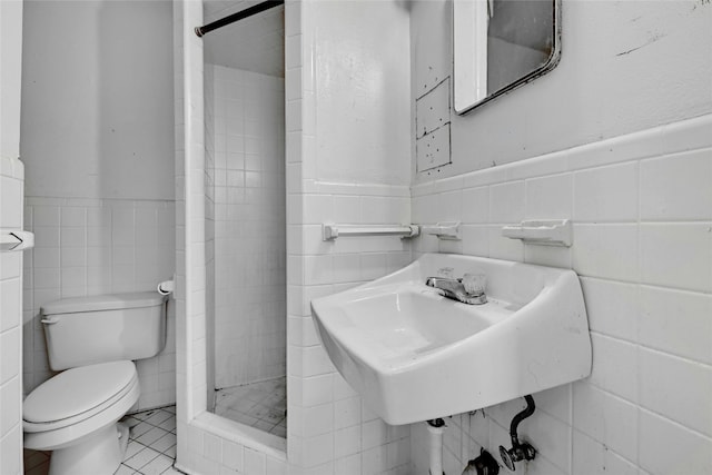 bathroom featuring a tile shower, tile walls, tile patterned flooring, and toilet