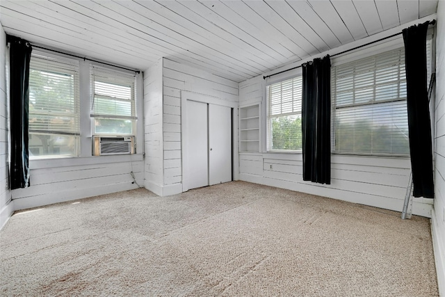 unfurnished bedroom featuring carpet flooring, multiple windows, and wooden ceiling