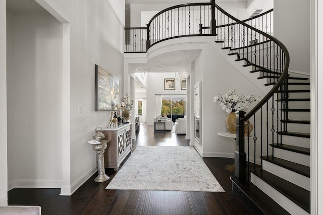 entrance foyer featuring a towering ceiling and dark wood-type flooring