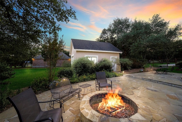 patio terrace at dusk featuring a yard and a fire pit