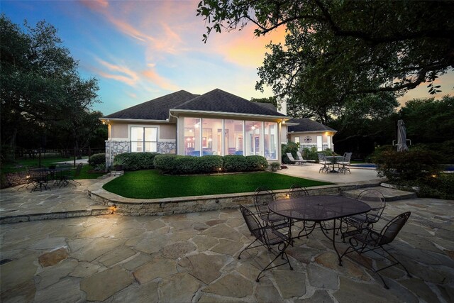 back house at dusk featuring a patio