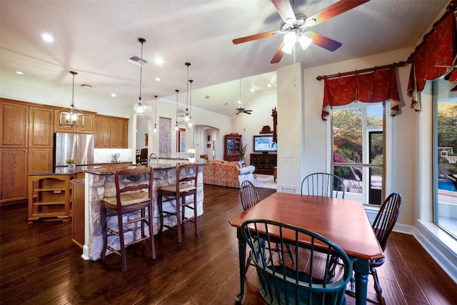 dining area featuring vaulted ceiling, ceiling fan, dark wood-type flooring, and a textured ceiling