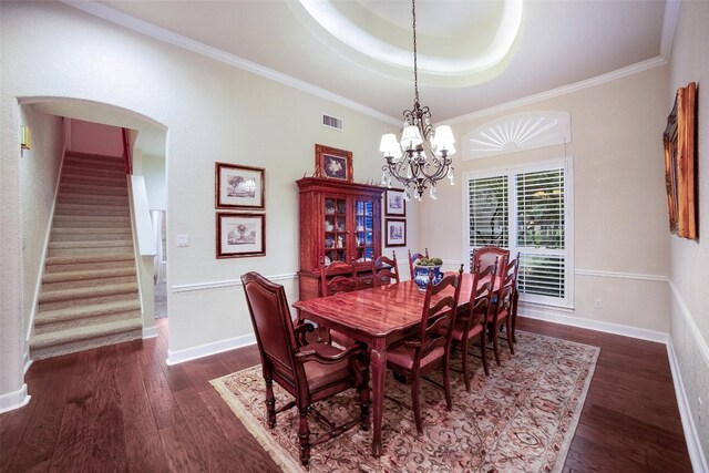 dining area featuring ornamental molding, a chandelier, a raised ceiling, and dark wood-type flooring