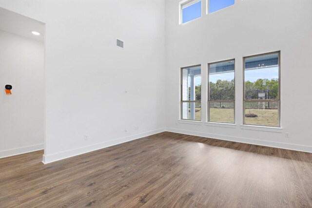 unfurnished room with dark wood-type flooring, visible vents, plenty of natural light, and baseboards