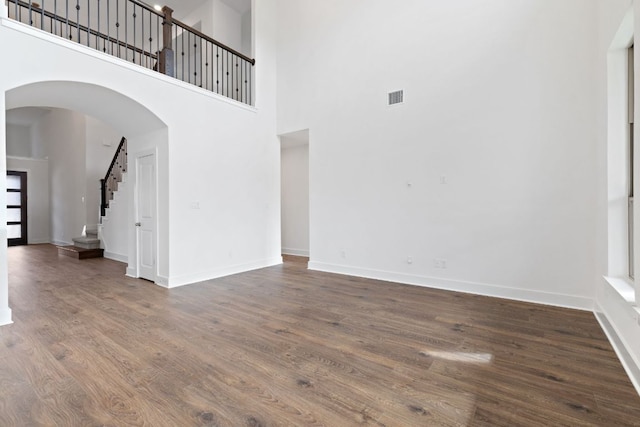 unfurnished living room featuring stairs, visible vents, baseboards, and wood finished floors