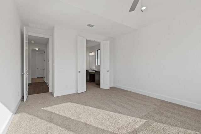 unfurnished bedroom with a ceiling fan, light colored carpet, visible vents, and baseboards