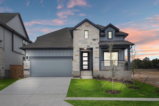 view of front of property with an attached garage, concrete driveway, stone siding, roof with shingles, and board and batten siding