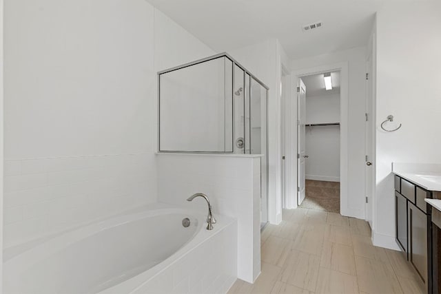 full bathroom featuring a stall shower, a walk in closet, visible vents, and a bath