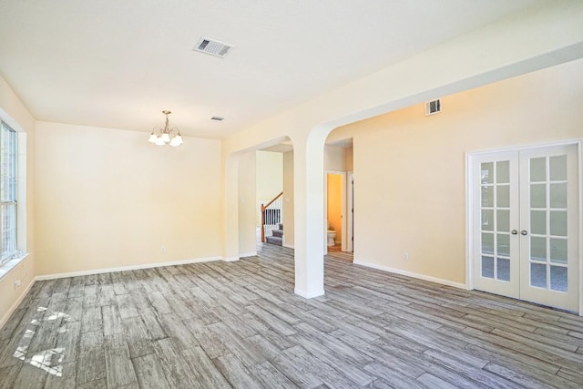 17006 Brewer Blackbird Dr, Pflugerville, TX 78660 - unfurnished living room with wood finished floors, arched walkways, a chandelier, french doors, and stairway