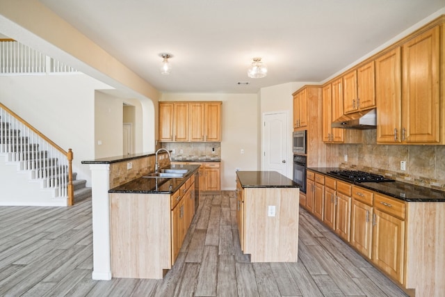 kitchen with sink, a center island with sink, backsplash, black appliances, and light hardwood / wood-style floors