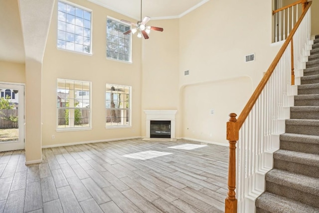 17006 Brewer Blackbird Dr, Pflugerville, TX 78660 - unfurnished living room featuring ceiling fan, wood finished floors, a towering ceiling, stairway, and plenty of natural light