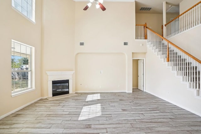 17006 Brewer Blackbird Dr, Pflugerville, TX 78660 - unfurnished living room with a towering ceiling, a ceiling fan, healthy amount of natural light, and wood finished floors