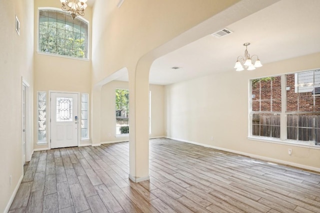 17006 Brewer Blackbird Dr, Pflugerville, TX 78660 - foyer with a chandelier, wood finished floors, arched walkways, and a towering ceiling