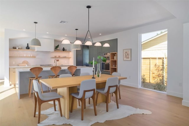 dining area with sink and light wood-type flooring