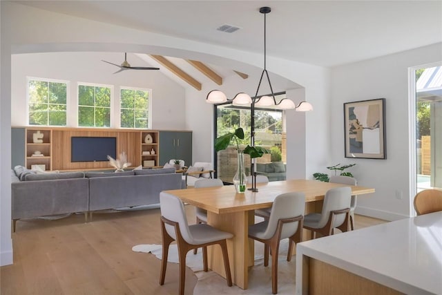 dining area with lofted ceiling with beams, ceiling fan with notable chandelier, and light wood-type flooring