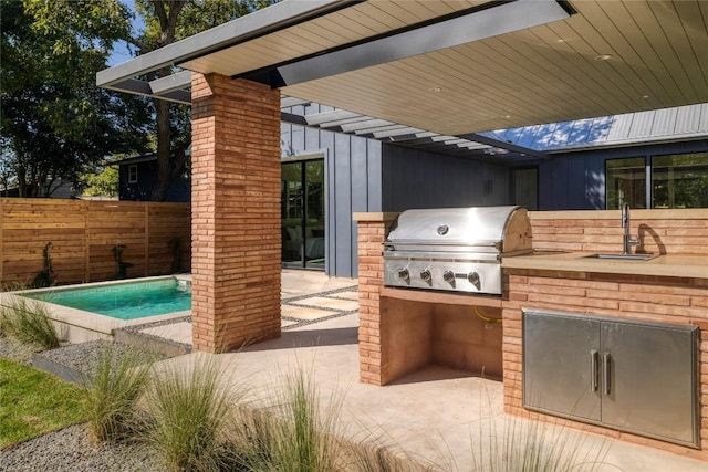 view of patio / terrace with exterior kitchen, area for grilling, sink, and a fenced in pool