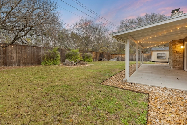 yard at dusk featuring a patio area and a storage unit