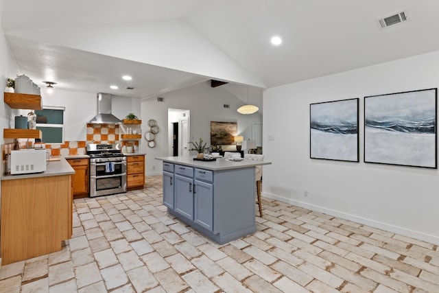 kitchen with a breakfast bar, hanging light fixtures, wall chimney exhaust hood, a kitchen island, and stainless steel range with gas stovetop