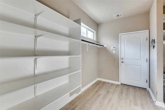 walk in closet with light hardwood / wood-style floors