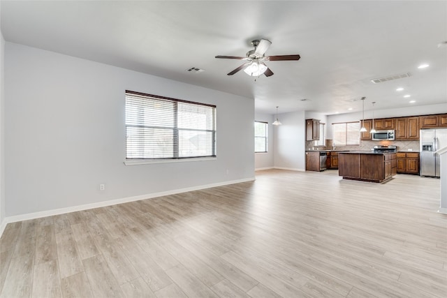 unfurnished living room with light hardwood / wood-style flooring, ceiling fan, and sink