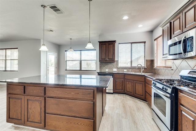 kitchen featuring light wood-type flooring, appliances with stainless steel finishes, a center island, and a healthy amount of sunlight