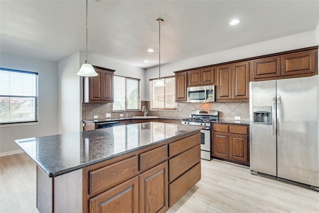 kitchen featuring pendant lighting, light wood-type flooring, stainless steel appliances, and a kitchen island