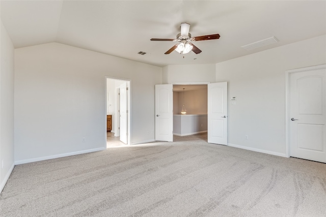 unfurnished bedroom with ceiling fan, light colored carpet, ensuite bath, and vaulted ceiling