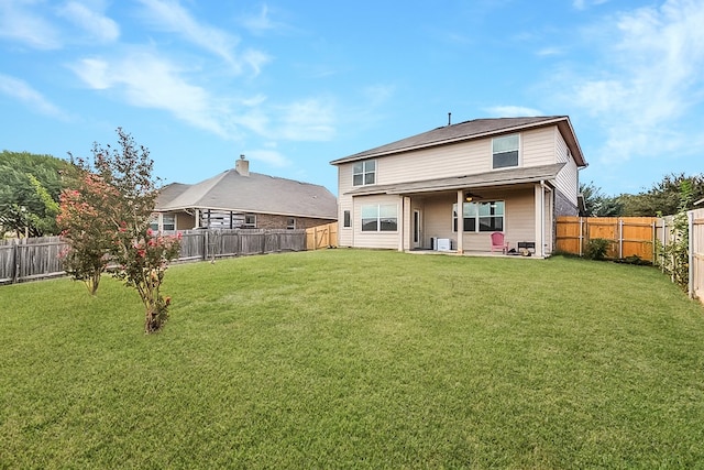 back of property with a yard and ceiling fan