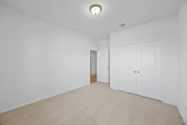 unfurnished bedroom with light carpet and a closet