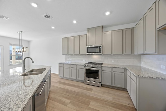 kitchen with gray cabinets, sink, stainless steel appliances, and light hardwood / wood-style flooring