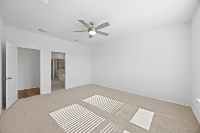 unfurnished bedroom featuring light colored carpet, ensuite bath, and ceiling fan