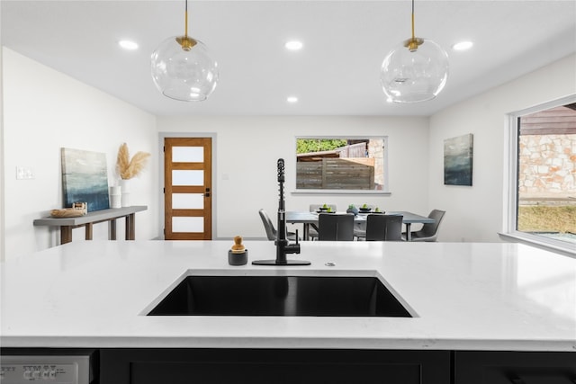 kitchen featuring sink, light stone counters, and decorative light fixtures