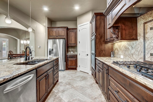 kitchen featuring light stone counters, stainless steel appliances, an inviting chandelier, decorative light fixtures, and sink