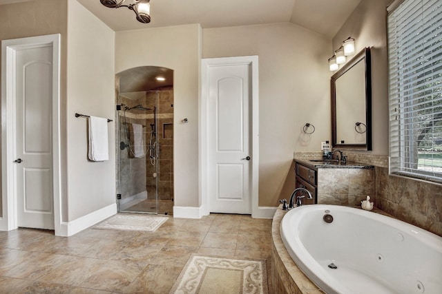 bathroom featuring independent shower and bath, vanity, and vaulted ceiling