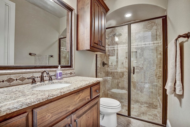 bathroom with walk in shower, vanity, toilet, and tasteful backsplash